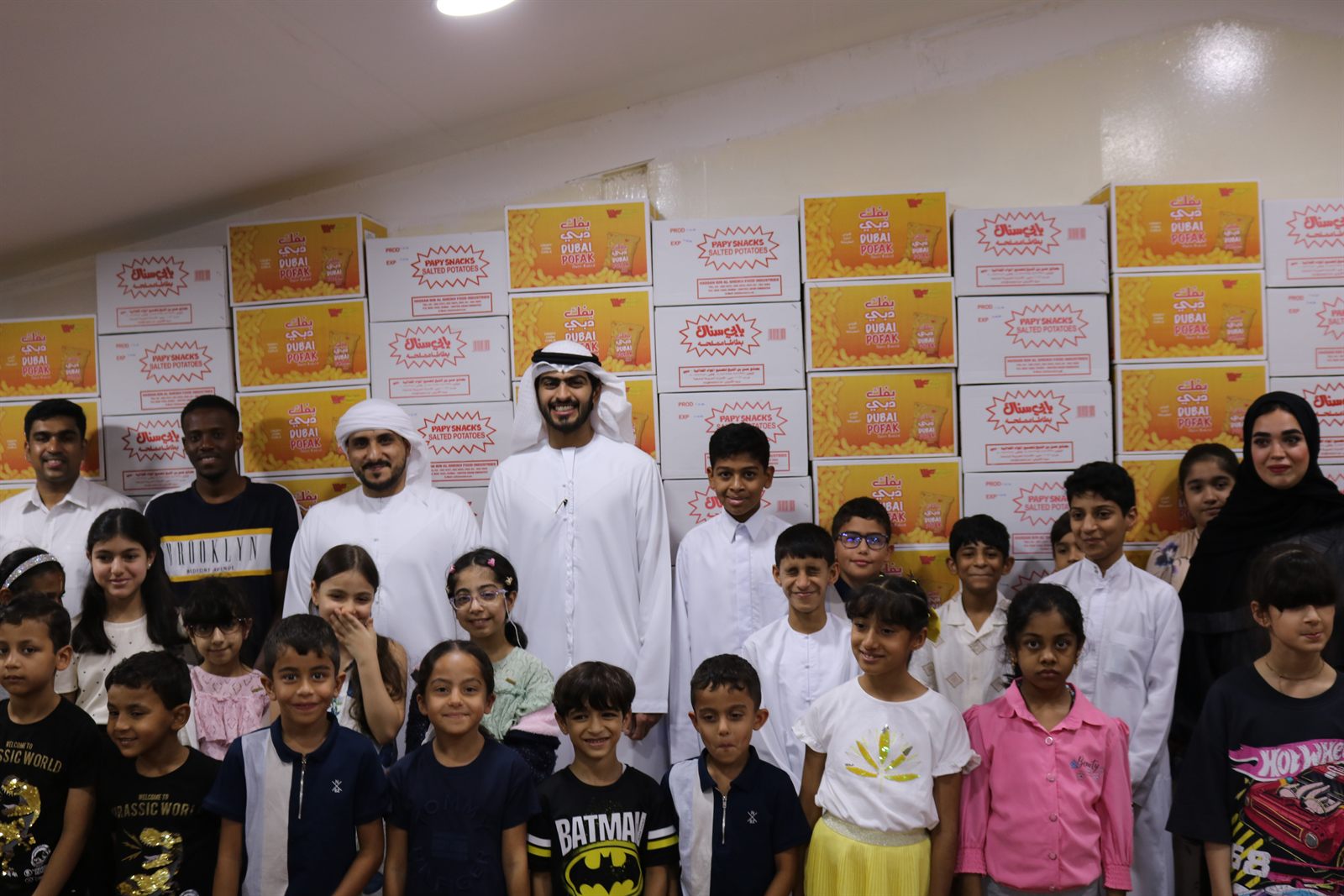 Staff and children standing together in front of stacked cartons of Modernfood product
