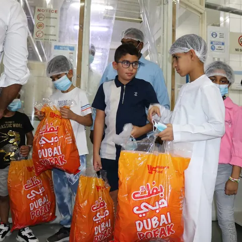 Children holding Dubai Pofak bags at a community visit